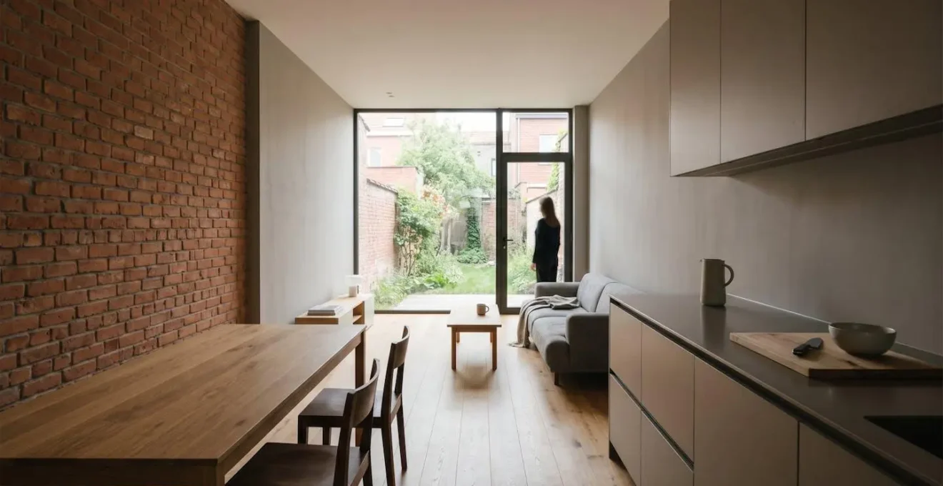 Intérieur calme d'une maison belge mitoyenne avec murs en briques, lumière naturelle apaisante et ambiance sereine illustrant le confort acoustique